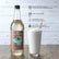 Sweetbird coconut syrup bottle with a glass of whipped cream and a straw on a wooden surface.