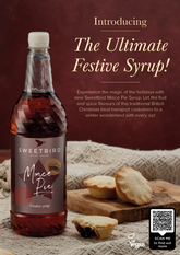 Bottle of Sweetbird Mince Pie Syrup with mince pies on a wooden board against a brown background.