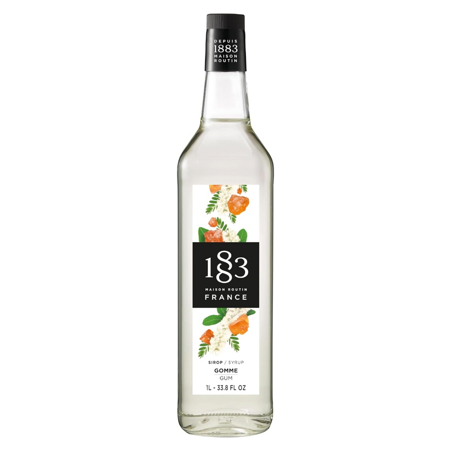 A bottle of 183 Maison Matrio France Gomme Cane syrup, featuring a clear glass bottle with a white and black label decorated with orange and green floral illustrations, set against a plain white background.