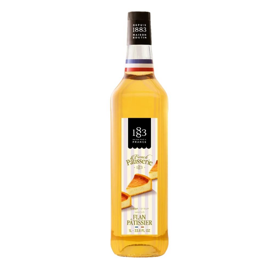 A bottle of 183 Flan Patisserie syrup filled with golden yellow liquid, featuring a white and black label with a slice of flan dessert illustration, on a solid white background.