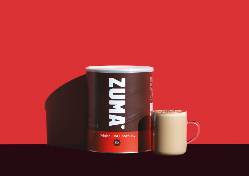 Zuma Original Hot Chocolate container and a mug on a red background